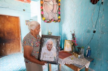 Older woman holding portrait of older man
