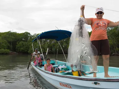 Woman in small boat holding a net with fish