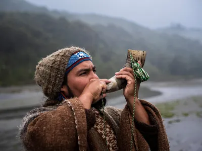 Indigenous man blowing decorated horn