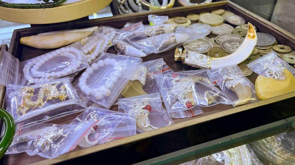 Tiger claws and teeth and ivory, labeled with prices, on a table.