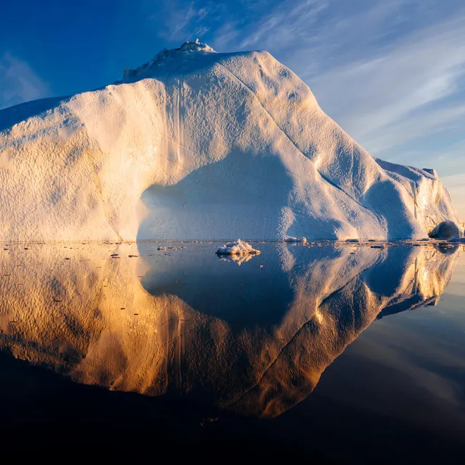 A snow covered peak juts into the water in Greenland