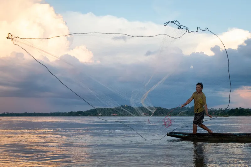 A fisher casts a net over the waters near near Na Village, Kong Island, Siphandone (4000 islands), Lao PDR