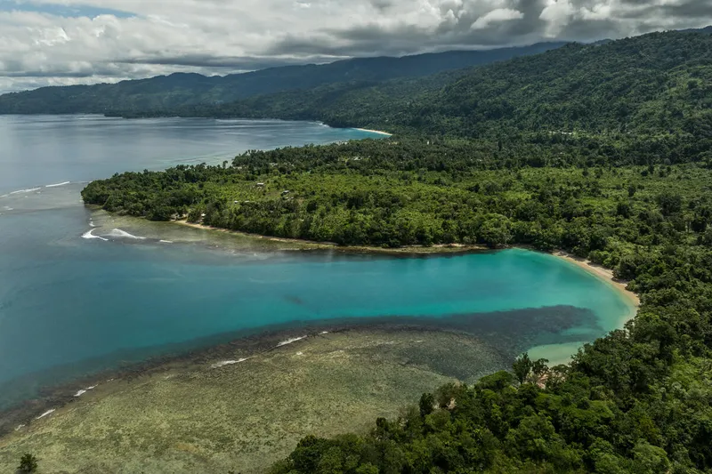 An aerial view of the coastline of Tokole Beach in New Britain, Papua New Guinea with the Gallowe Village in the distance