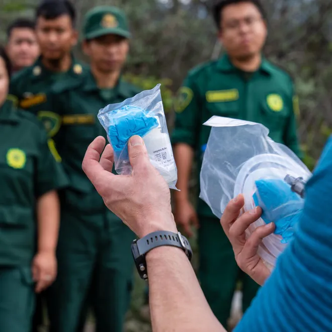 Hands holding package of gloves in front of trainees