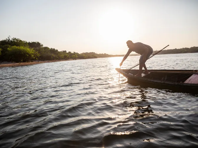 Fisherman Cleucejaster Batista da Silva stands on the edge of his boat and uses a bow and arrow to fish in Lake Anumã, Brazil.