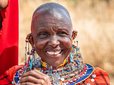 A woman in bright African clothing smiles warmly at camera