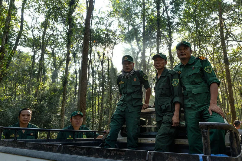 Five ranchers sit and stand on a vehicle in a forest in Bhutan