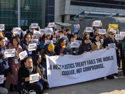 A group of people stand in front of a banner reading "A weak plastics treaty fails the world. Courage, not compromise."