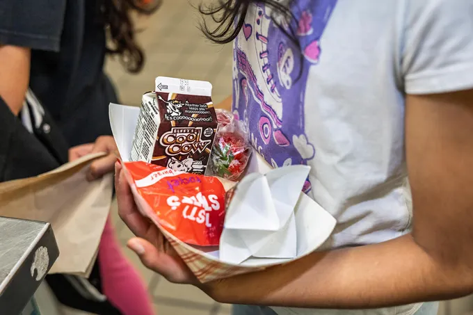 A closeup of a plate of food held by a student including chocolate milk
