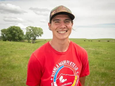 Ehakala "Hawkey" Cummings, Intertribal Buffalo Council, smiles as he stands in a field of buffalo in South Dakota