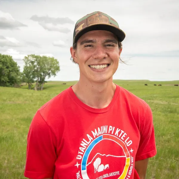 Ehakala "Hawkey" Cummings, Intertribal Buffalo Council, smiles as he stands in a field of buffalo in South Dakota