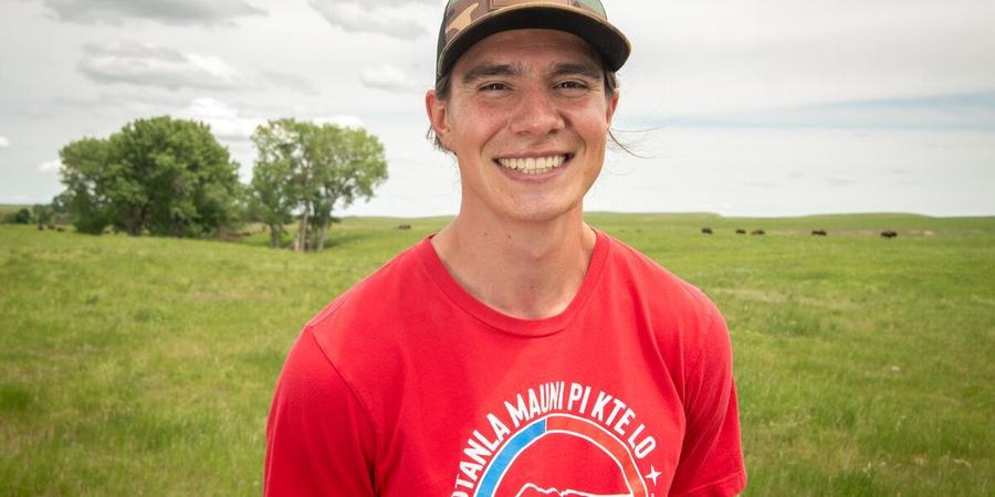Ehakala "Hawkey" Cummings, Intertribal Buffalo Council, smiles as he stands in a field of buffalo in South Dakota