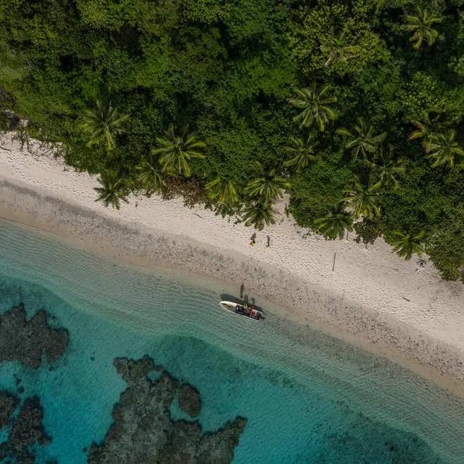Aerial photo of the Fiji coastline showing a small boat next to a sandy beach