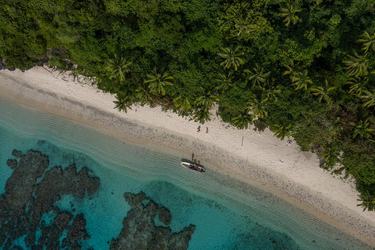 Aerial photo of the Fiji coastline showing a small boat next to a sandy beach