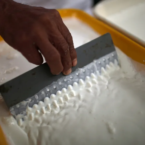 A hand runs a comb through liquid latex