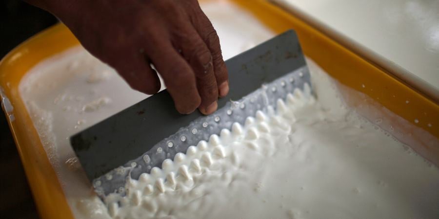 A hand runs a comb through liquid latex