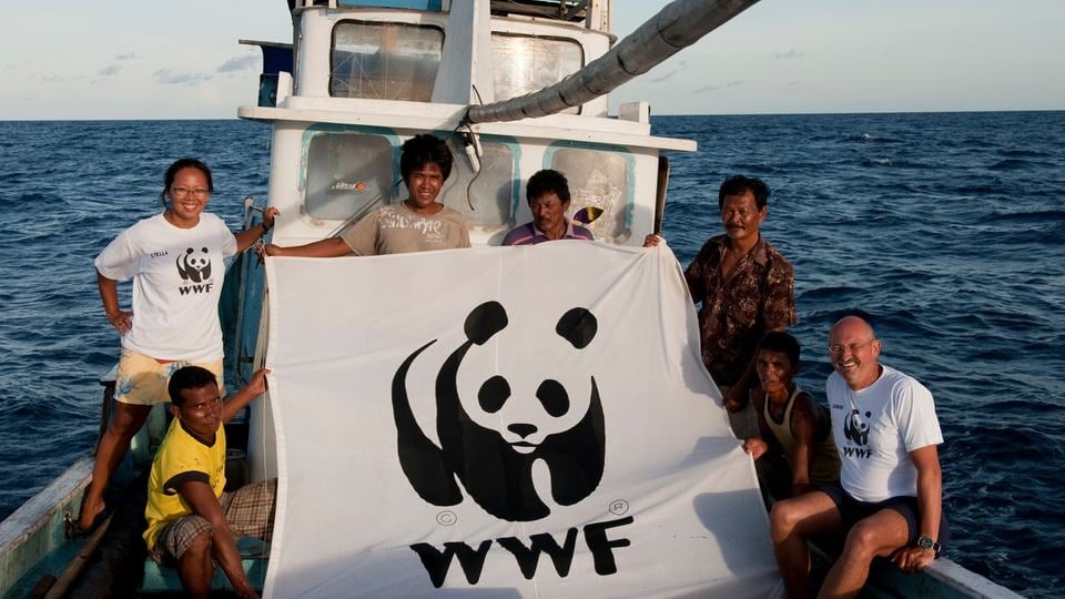 Tuna fishermen in Indonesia pose in a boat with a WWF flag