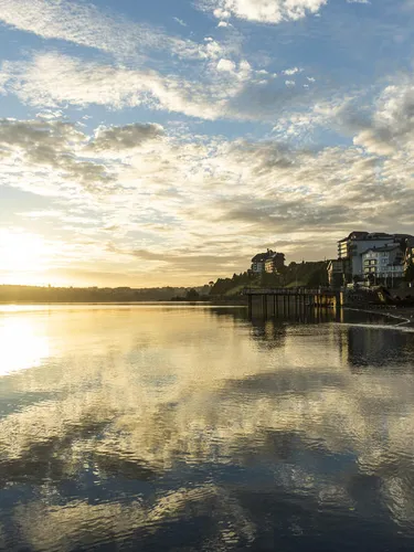 Sunrise on the waterfront of Puerto Varas, Chile shows buildings reflected in the water