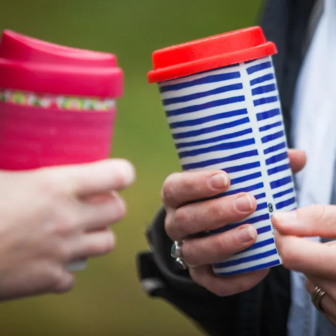 Hands holding reusable coffee cups
