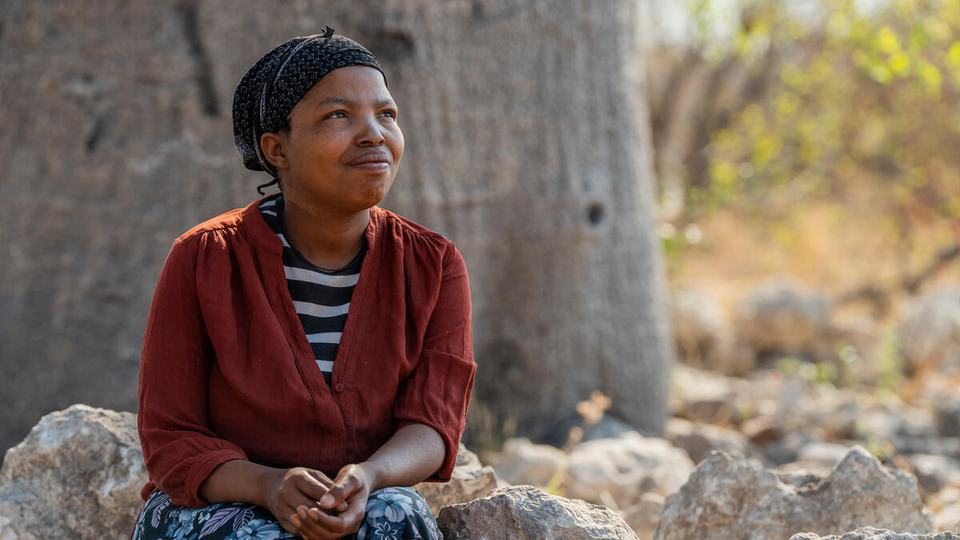 Hulda Kagece, Boabab Survey Team Lead and Trainer, sits under a baobab tree in Nyae Nyae Conservancy, Namibia