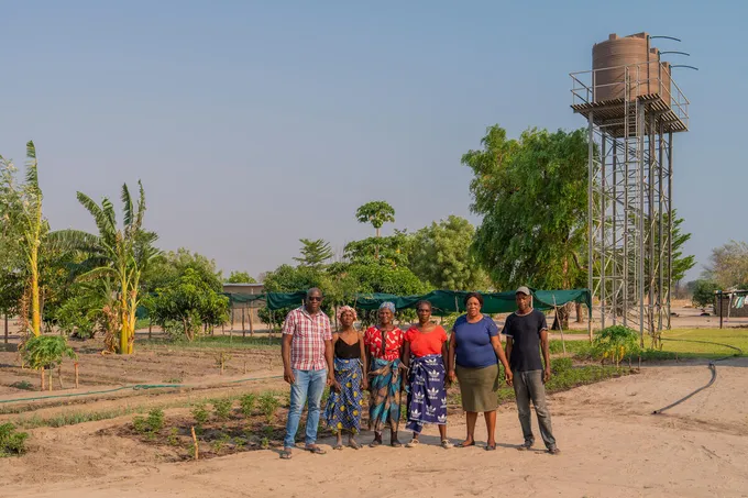 African community members line up for photo with water towers in background