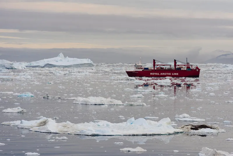 Royal Arctic Line cargo vessel passing through icebergs near Ilulissat, Greenland