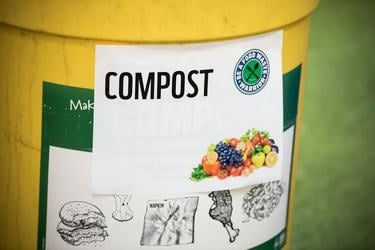 A closeup of a yellow compost bin with a sign that shows some of the foods that can go in the bin