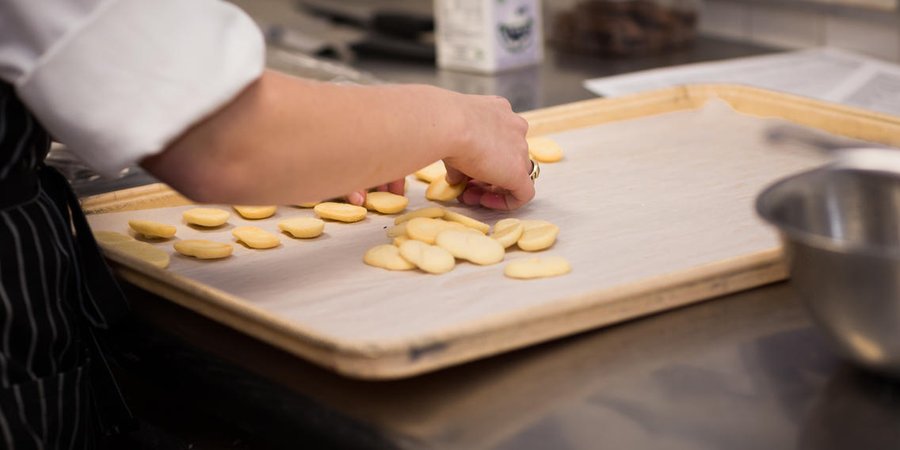 A person lays cookies out on a baking pan