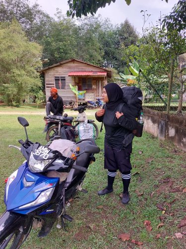 Mila stands beside her motorcycle wearing a backpack as she gets ready to go on patrol