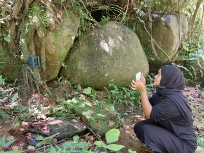 Female ranger Mila tests a camera trap that is attached to a tree in the forest