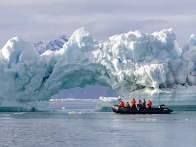 Wide shot of a group of people in boat that approaches an ice ark from a glacier.