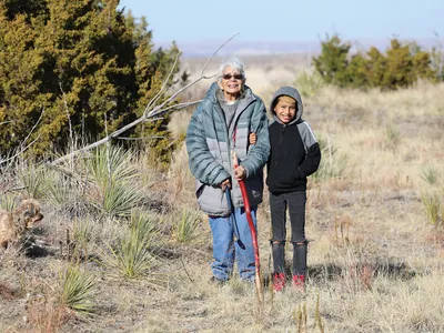 Older woman and child standing amongst scrub plants
