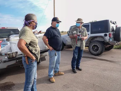 People in masks standing near trucks