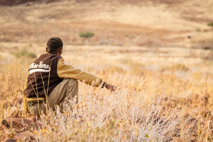 Man crouching in tall grass looking at landscape