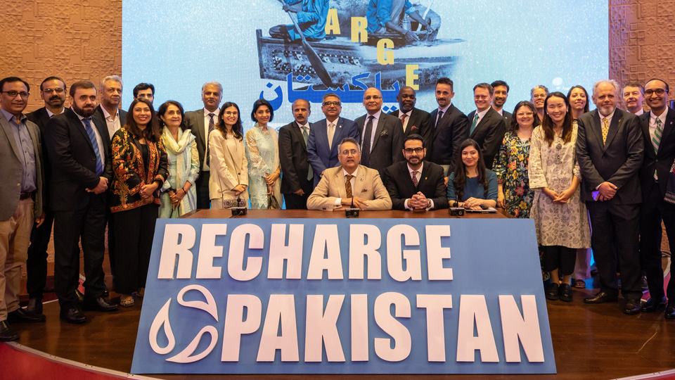 A group of people standing with a sign saying Recharge Pakistan