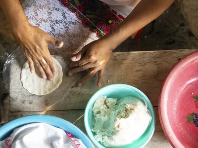 an overhead view of a woman's hands mixing ingredients to make tortillas
