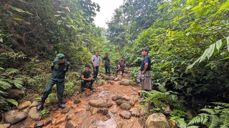 Several men stand in a streambed examining waterflow