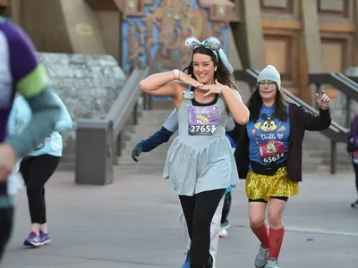 Woman running in a race in Disney World looking at the camera smiling.