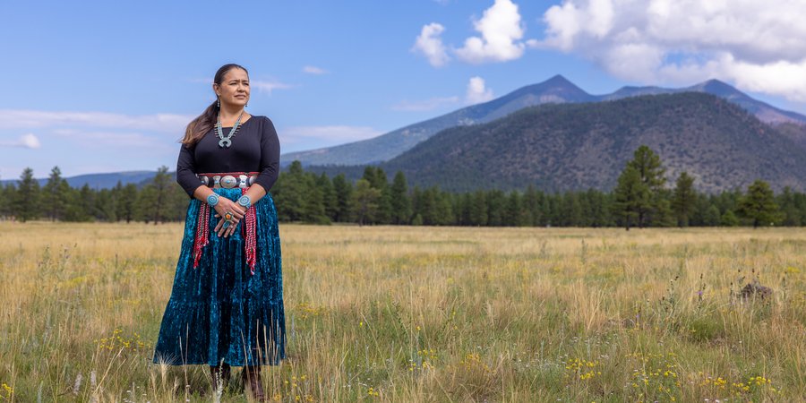 Clara Pratte, in traditional dress, standing in front of mountains