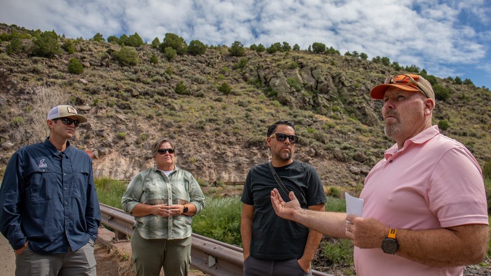 Four people stand in front of low-growth shrubbery in a desert ecosystem