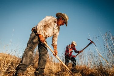 Two men in hats use tools to work the land in the Rio Grande