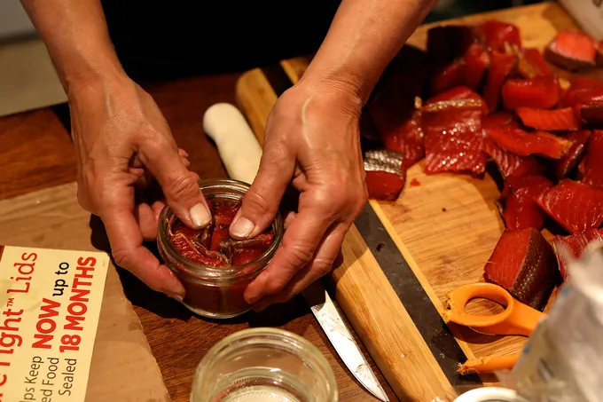 Closeup of person packing salmon in jar