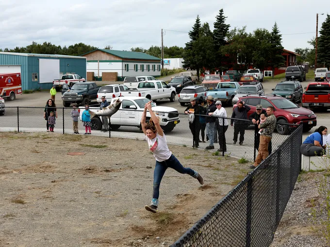 Woman tossing large fish with onlookers