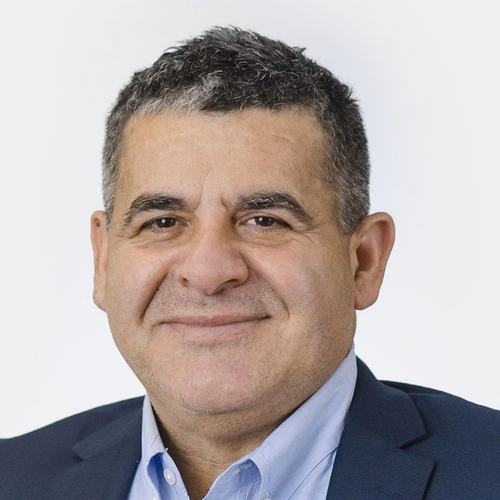 A head shot of Sergio Nates, who has black hair and wears a blue shirt and jacket