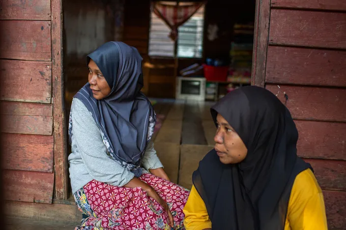 Two women in headscarves sitting by an open door