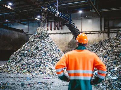 Plastic falling from conveyor belt onto pile at facility