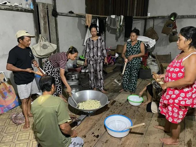A group of women stand around a large cauldron of coffee