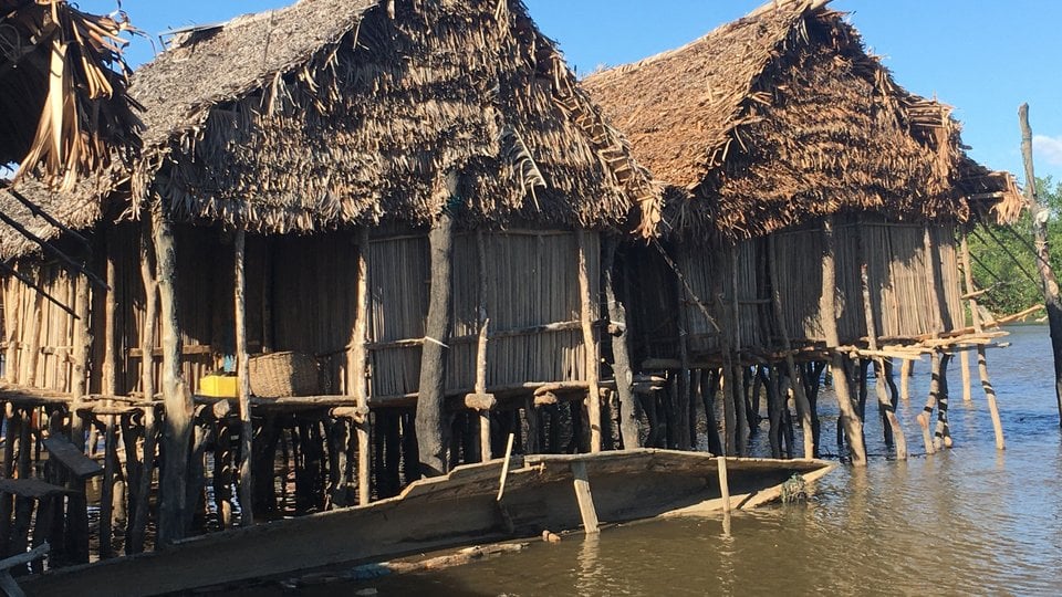Three bungalows sit on stilts above murky water