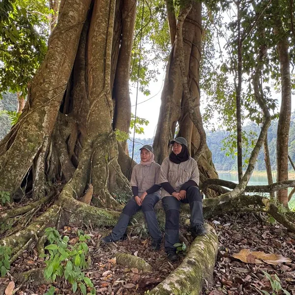 Rangers Mila and Suzana stand by a large tree in the forest