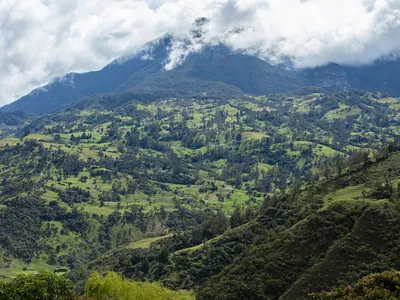 An aerial view of a mountain landscape with a hovering cloud in the PNN Chingaza buffer zone, Cundinamarca, Colombia